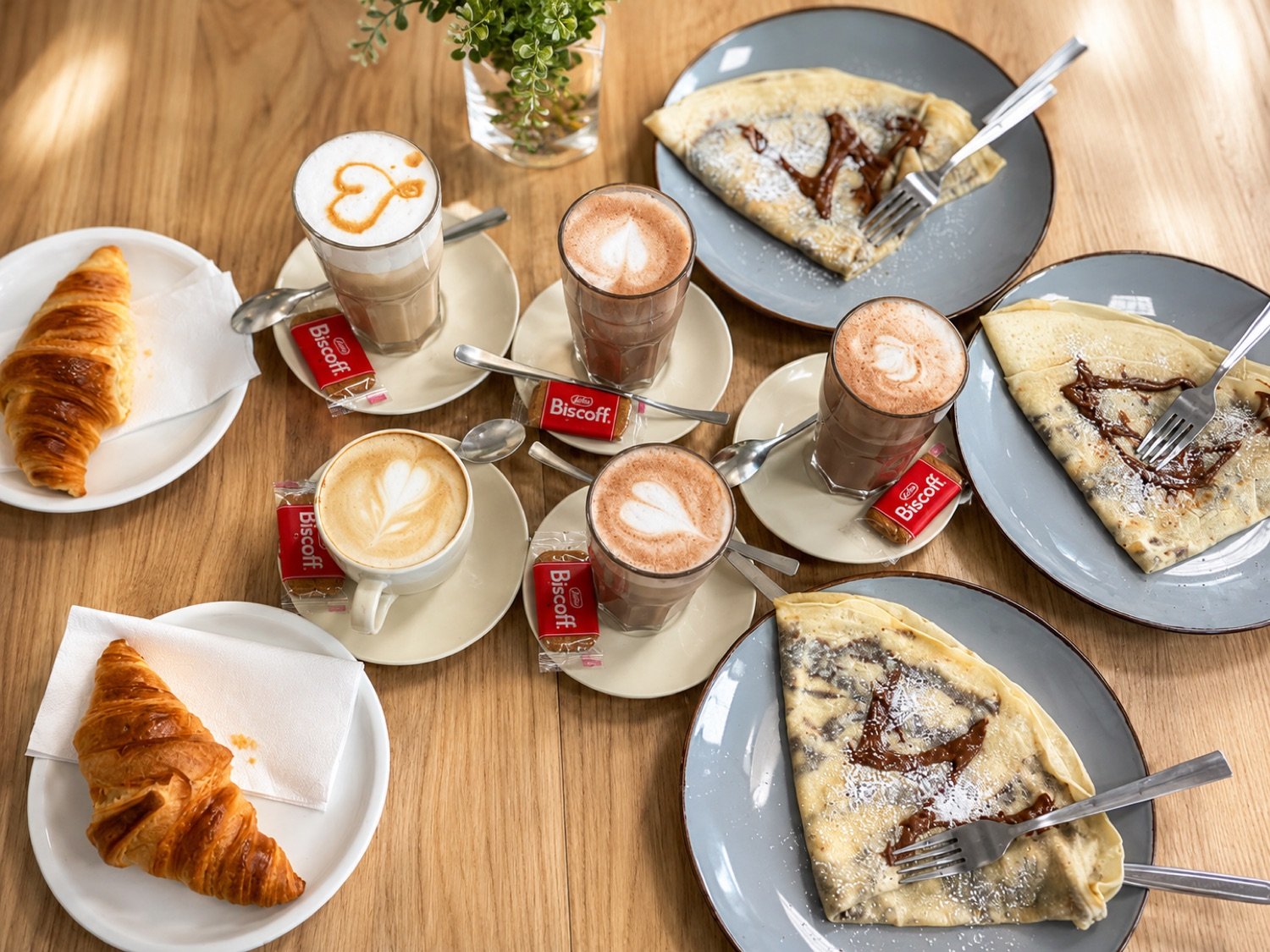 Cappuccino, Latte und Crêpes mit Schokolade auf Holztisch